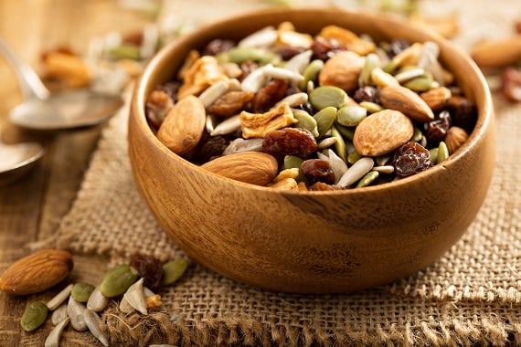 Dried fruit and nuts trail mix with almonds, raisins, seeds and apples in a wooden bowl