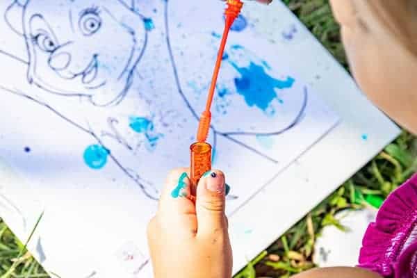 girl creating bubble art using blue ink