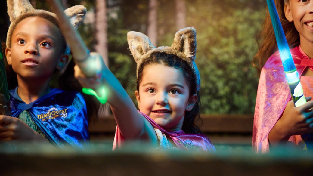 little girl placing a cape on little girl at MagiQuest interactive game