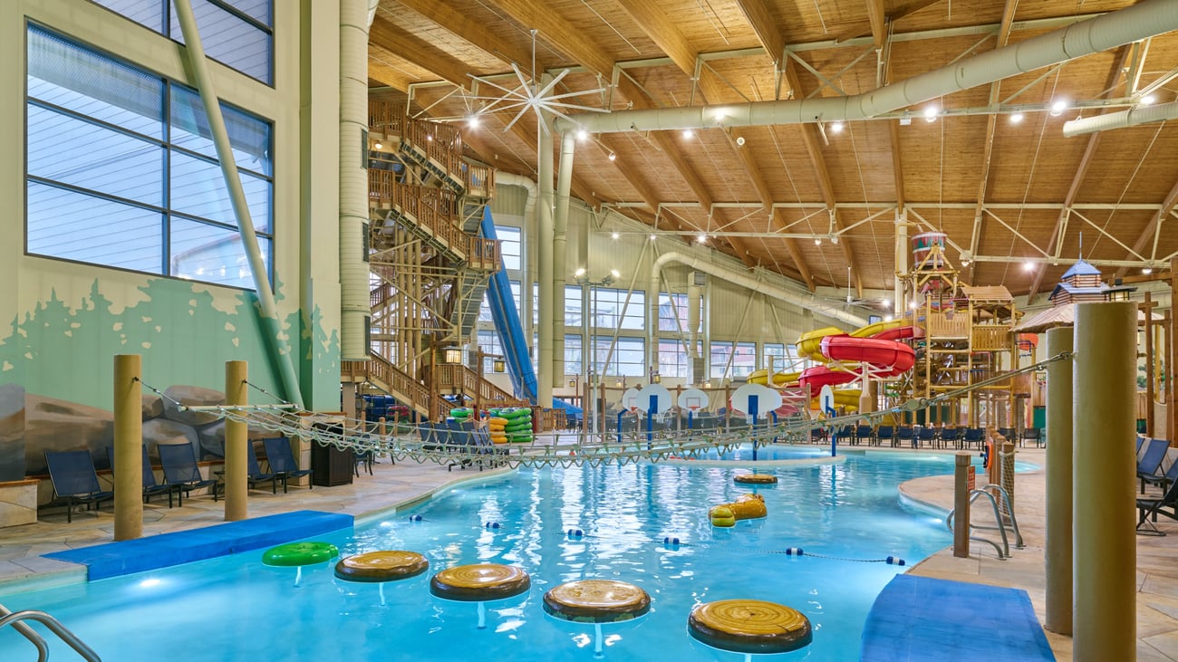 A girl balances on a lily pad float in indoor pool