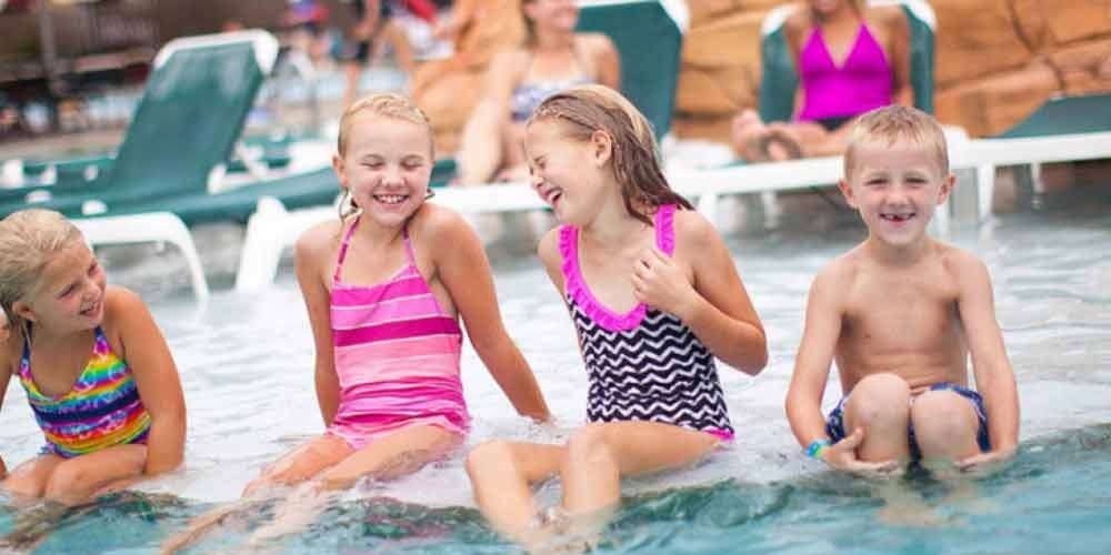 Four kidslaugh and  jump into outdoor pool