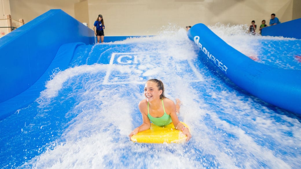 A child rides on a yellow boogie board in the water attraction 