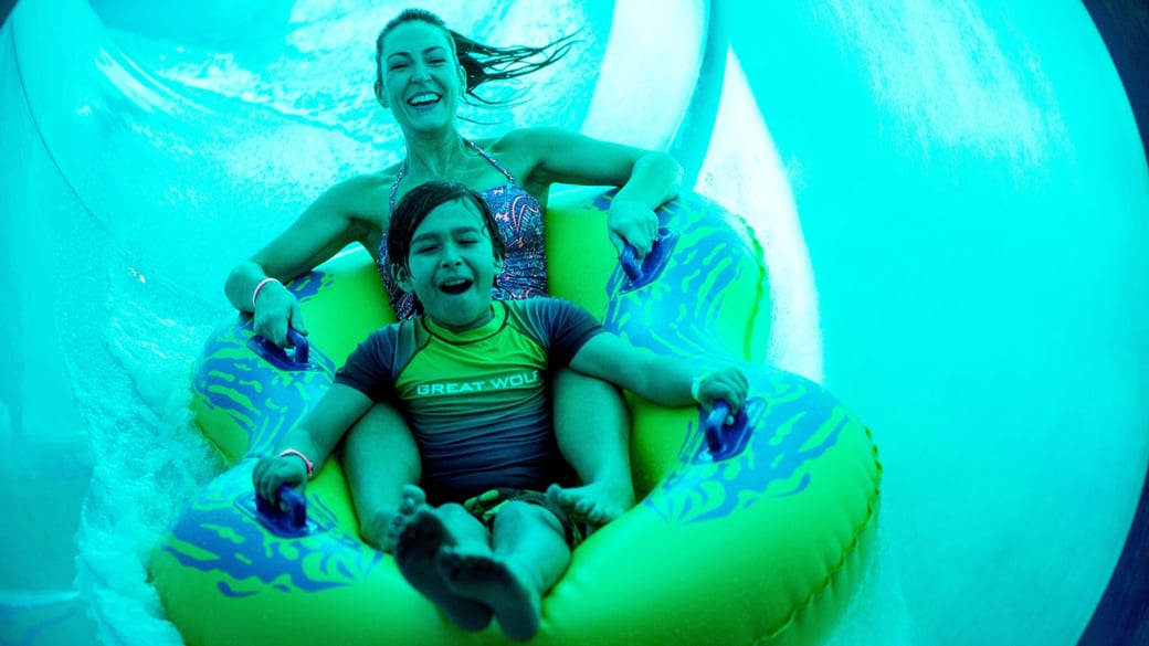 Mother and son in a tube racing down a yellow waterslide 