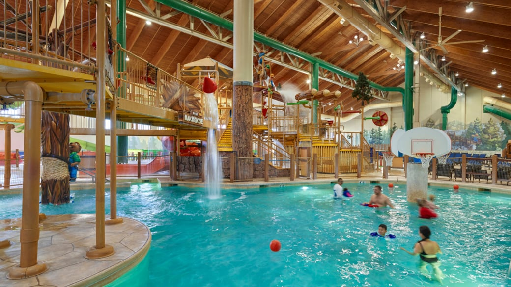 family playing basketball in indoor pool 