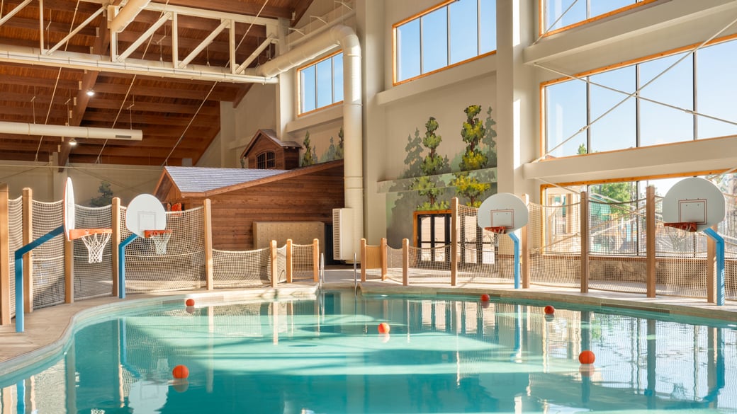 family playing basketball in indoor pool 