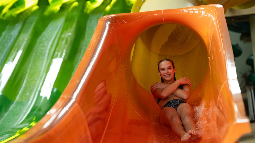 a girl coming down a yellow slide