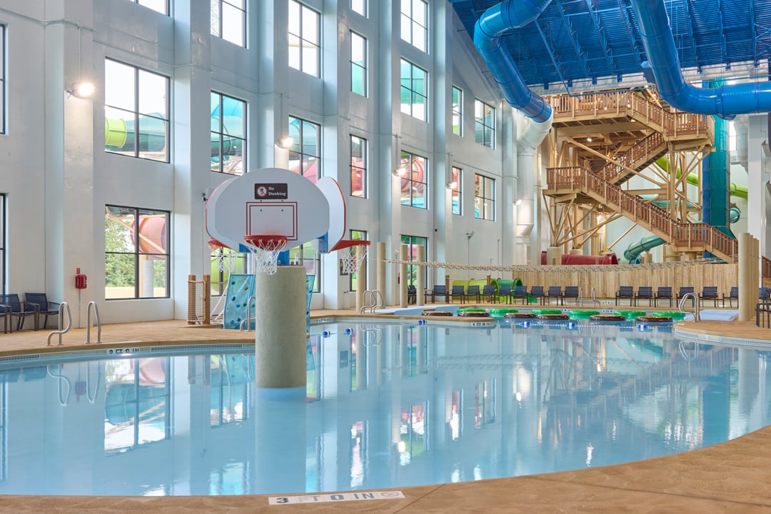 family playing basketball in indoor pool 