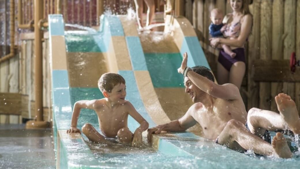 dad high fives his son as they come down a waterslide 