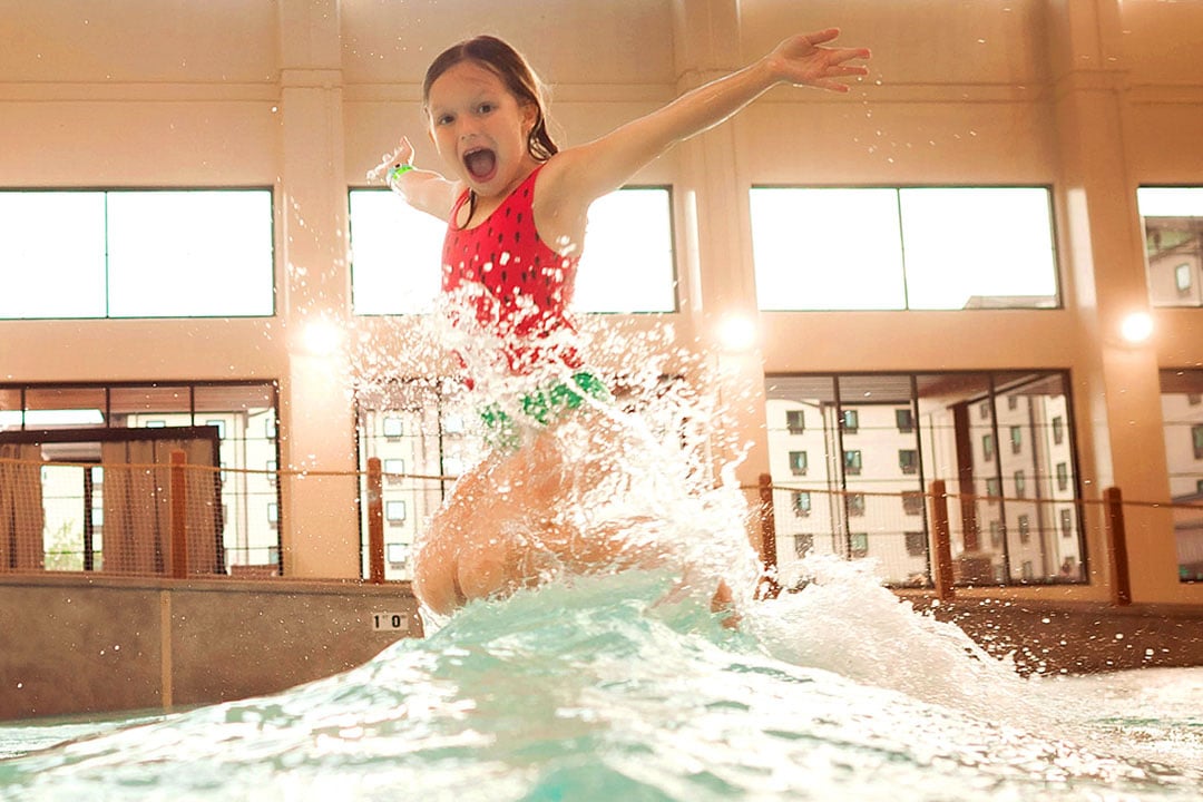 Little girl jumping in a pool