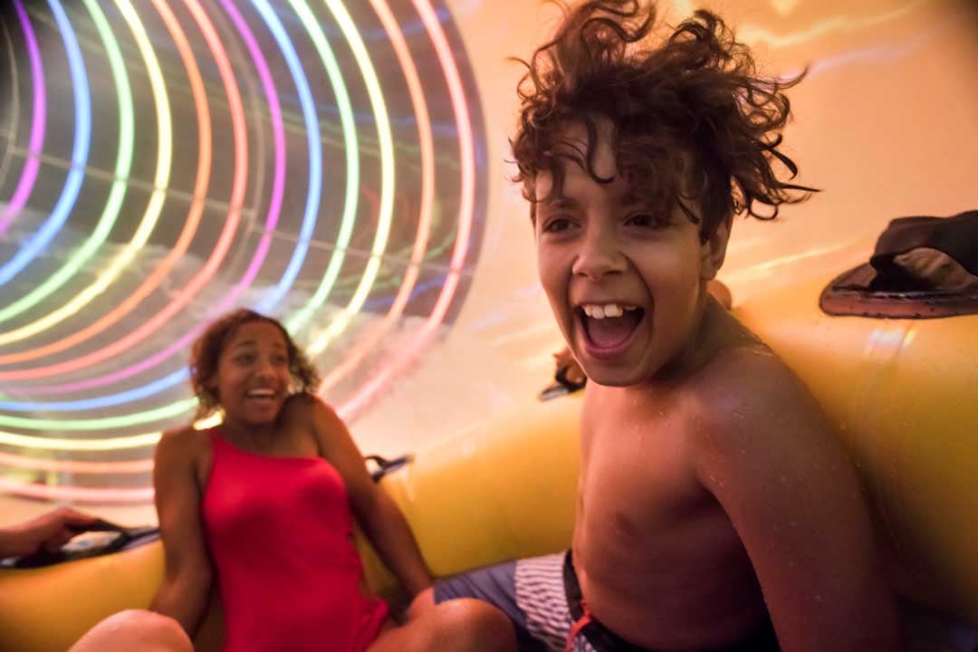 Young boy sliding down a water slider with his mother 