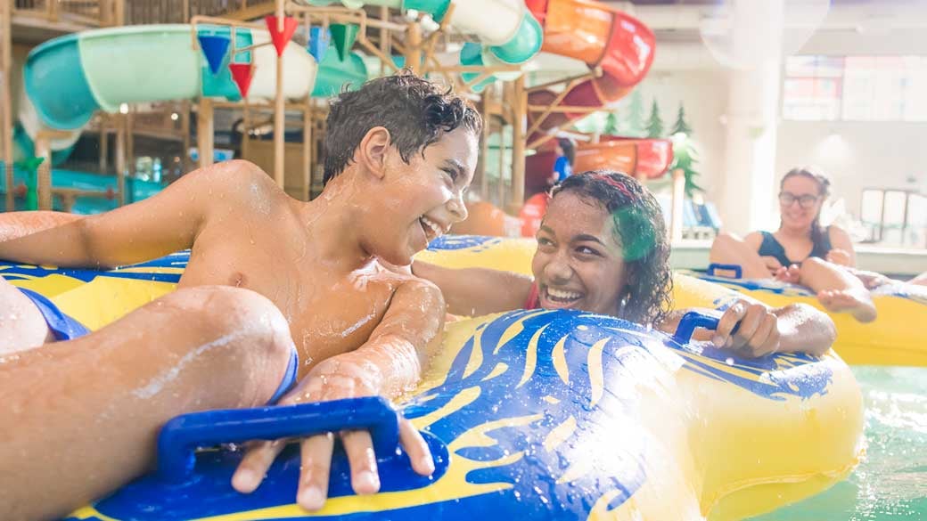 two teenagers share a tube down the lazy river