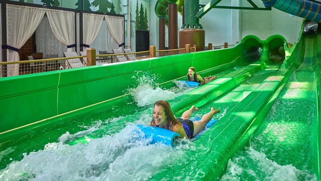 Two teenagers sliding down a water slider