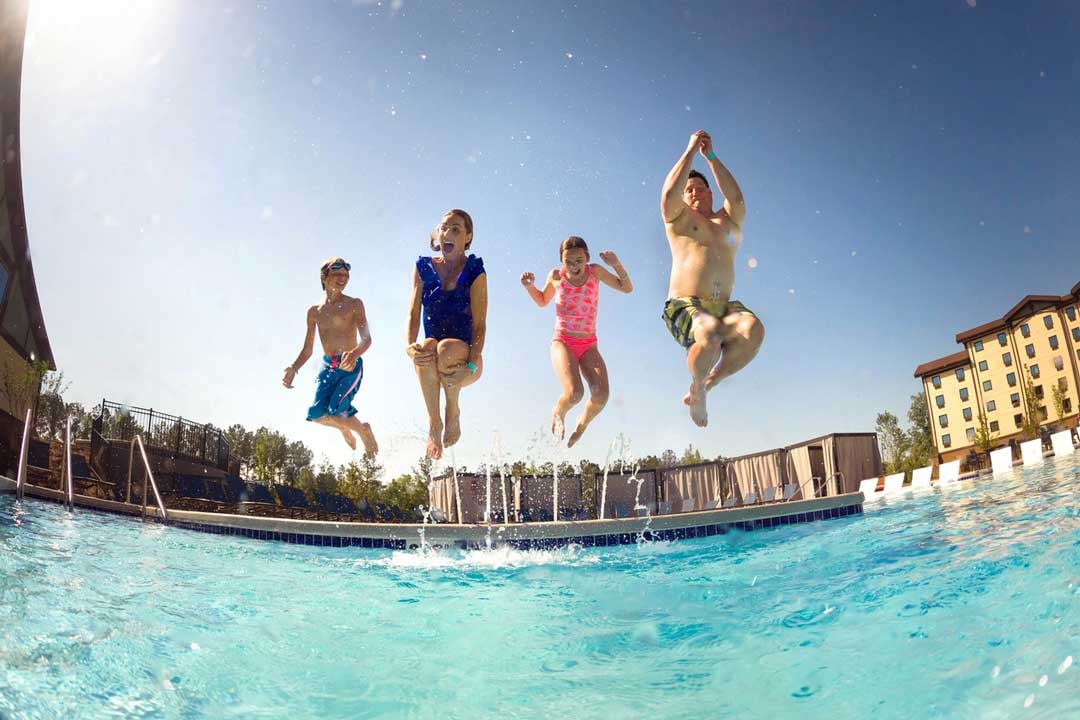 family jumping into a pool 