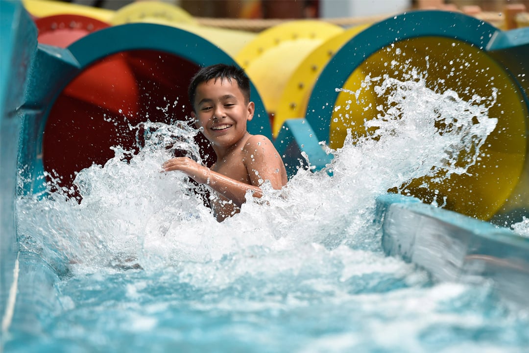 young boy sliding down on a water slide