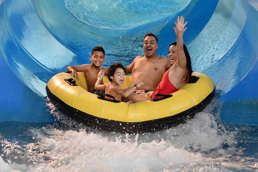 family of sliding down on a indoor water slider 