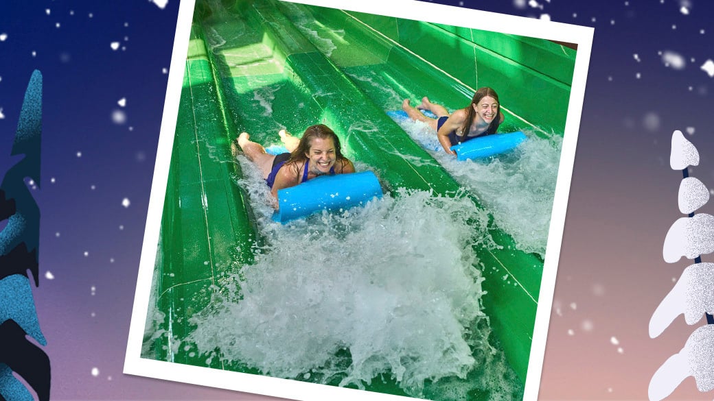 Two teenagers sliding down a water slider