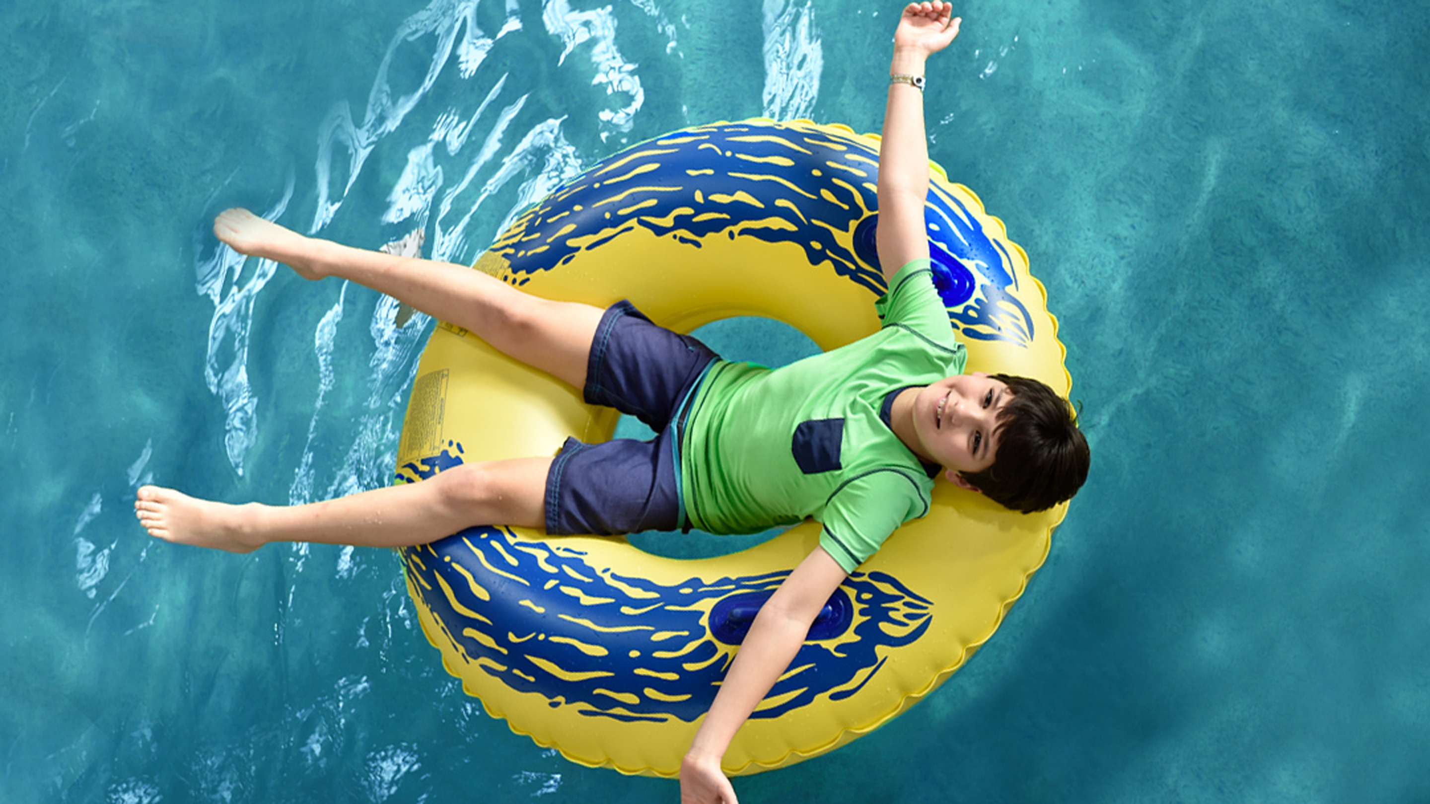 Young boy enjoying an indoor pool on a green float at Great Wolf Lodge