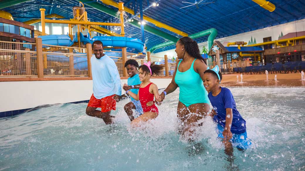 family enjoying splashing in wave pool in waterpark