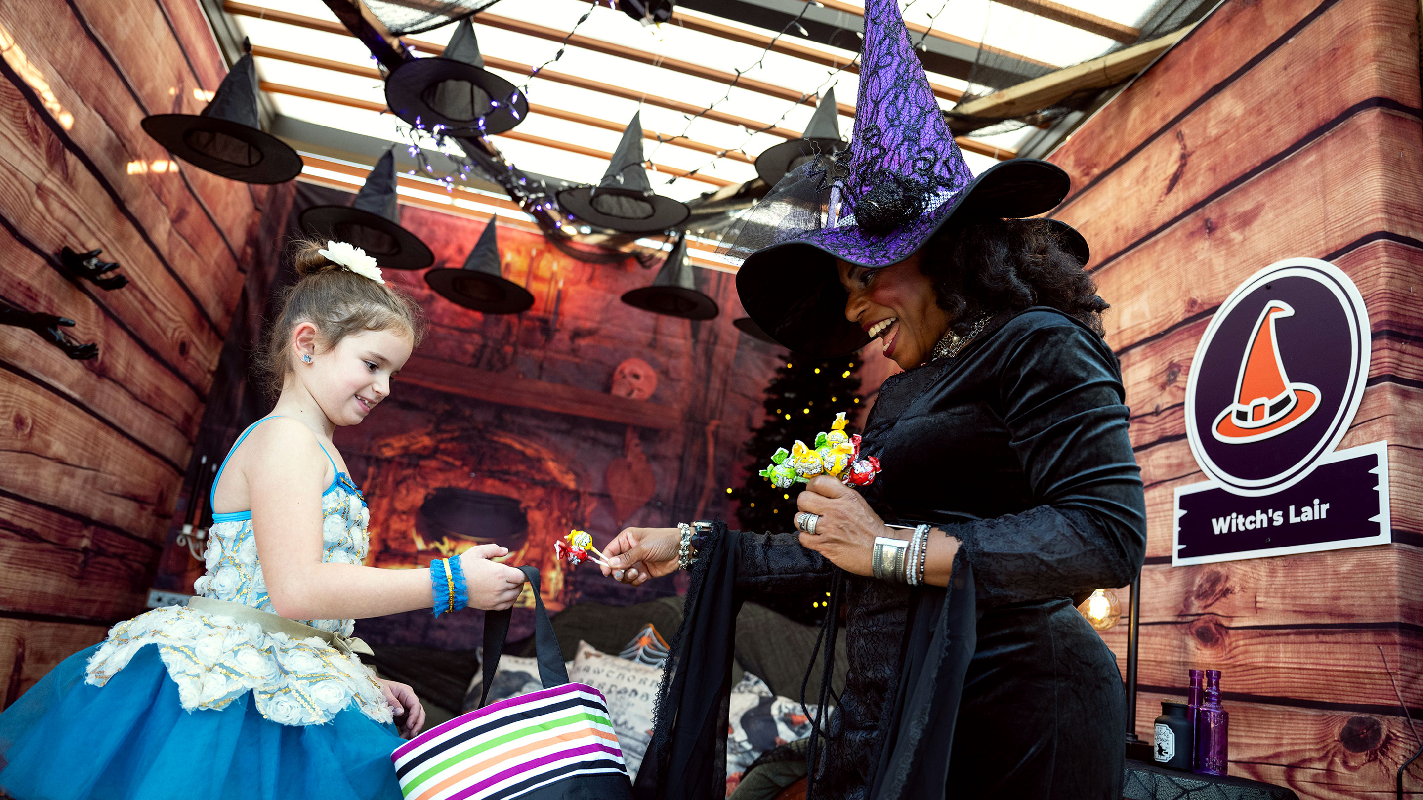 lady in a witch costume handing candies to kids