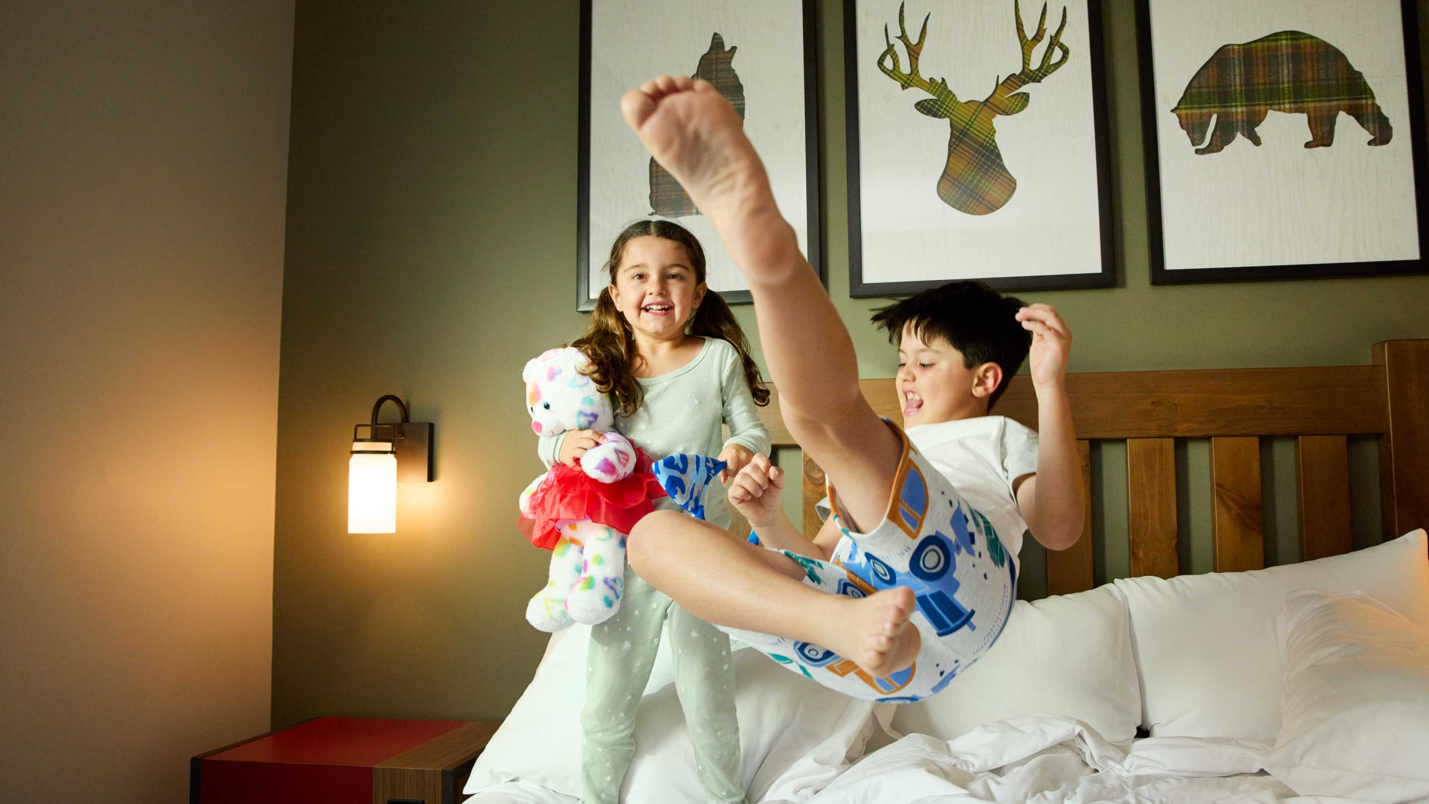 boy and girl laughing and jumping on the bed