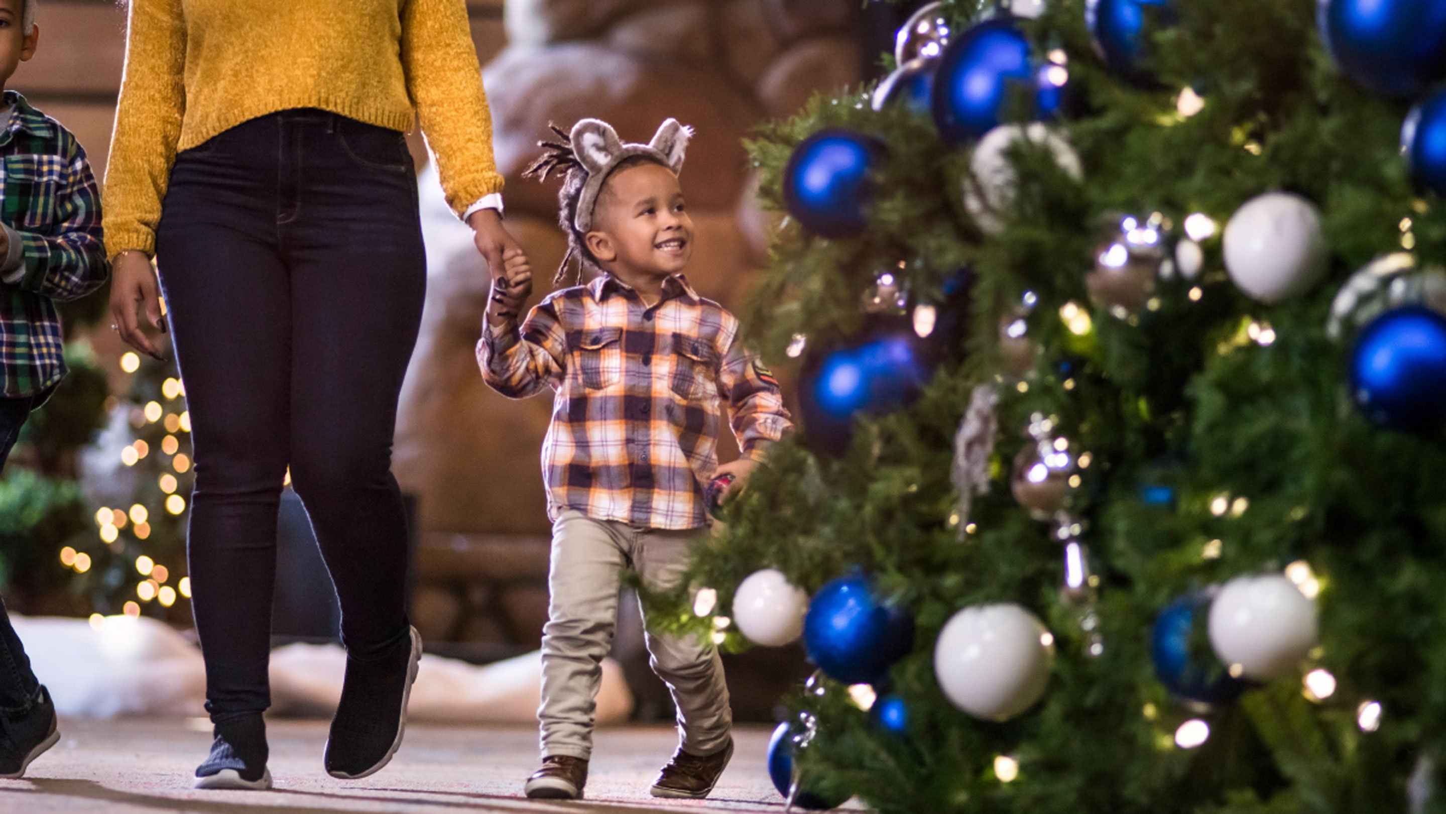 Young boy having winter fun near a holiday tree