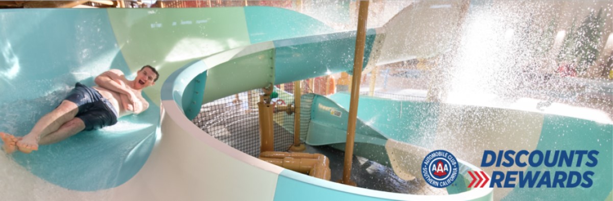 A man smiles while twisting down a slide at Great Wolf Lodge indoor water park and resort.