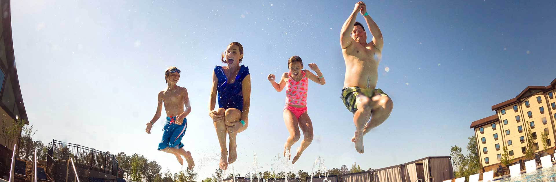 A family of four is jumping into an outdoor pool