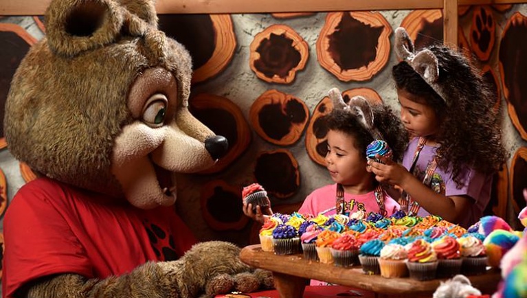 Wiley the Wolf  looks at cupcakes with two children 