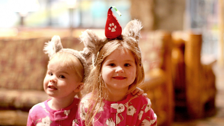 Two girls wearing wolf ears smile