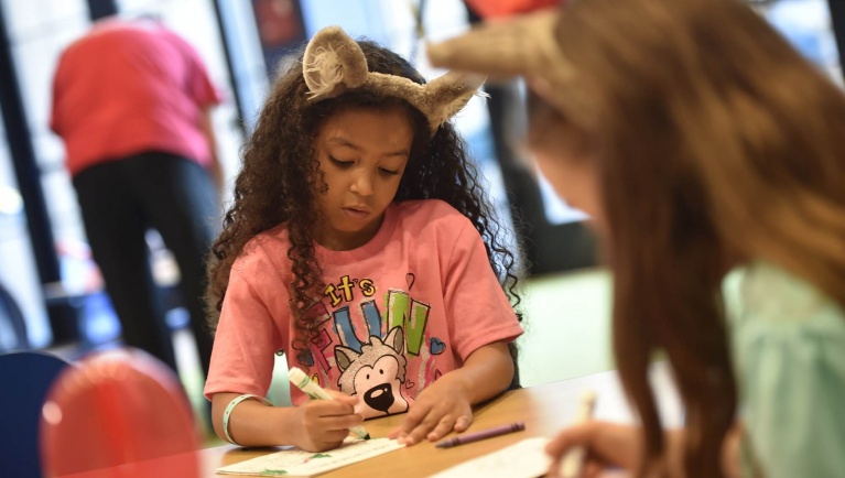 A girl colors while at Camp H.O.W.L.