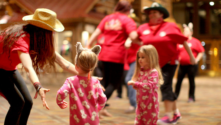 Great Wolf Lodge pack members lead two young girls in a dance