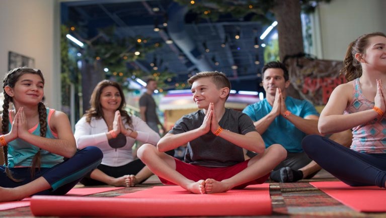 Families sit on red mats doing yoga