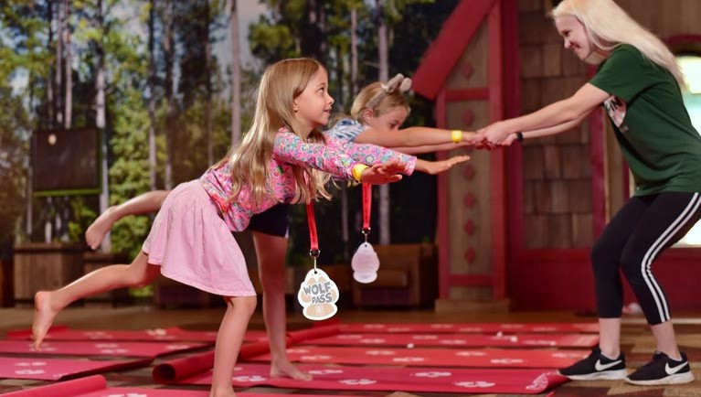 Two girls doing a yoga pose with an employee