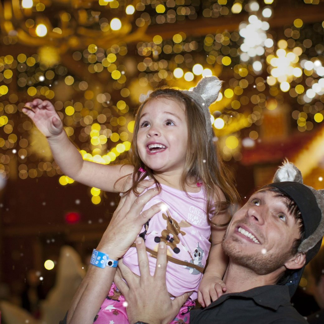 father and daughter enjoying indoor snowfall