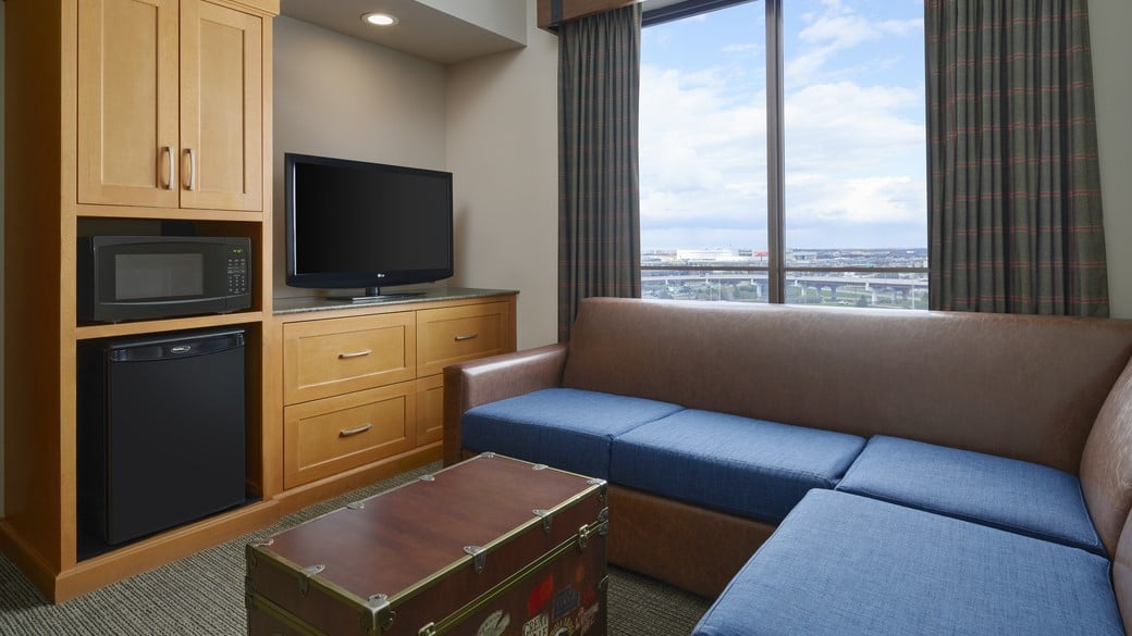 The living areas with L-shaped couch and TV in the Deluxe Family Suite Accessible Bathtub