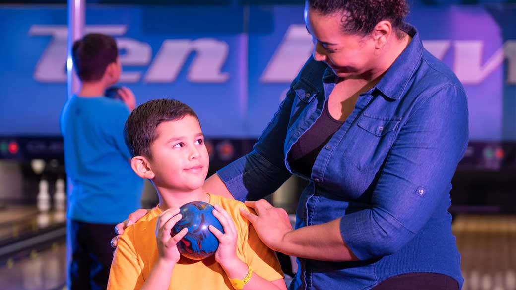 A mother and his kid enjoying bowling