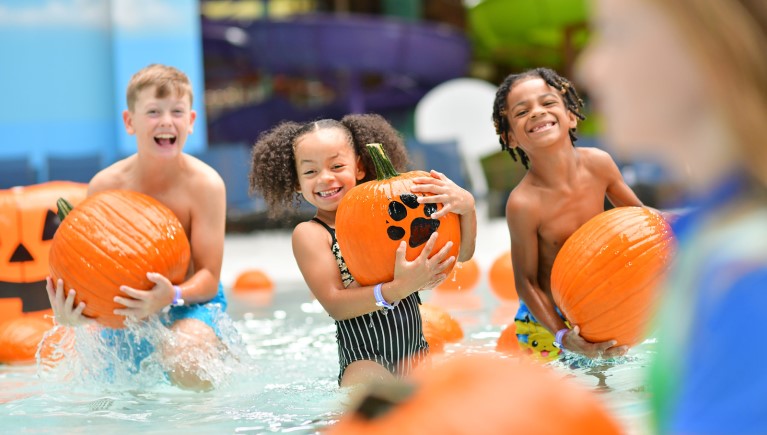 Kids playing with pumpkins in pool