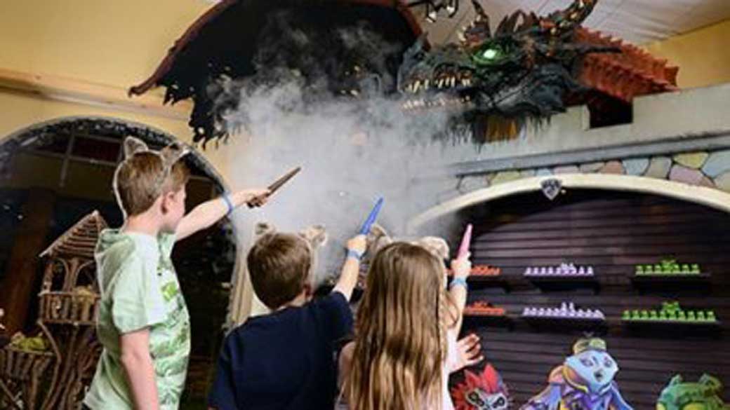 Kids target a dragon with their wands at Magiquest