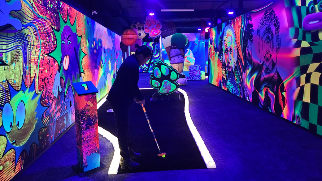 Young woman enjoying indoor glow golf at Ripleys Crazy Golf