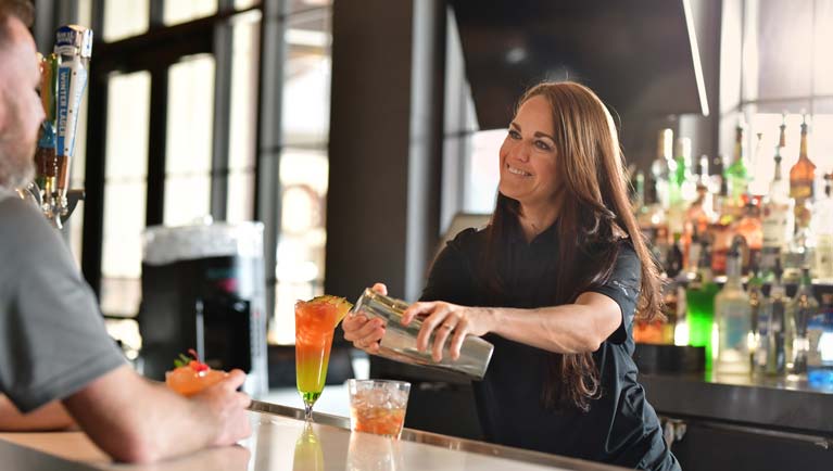 female bar tender serving cocktail to a guest