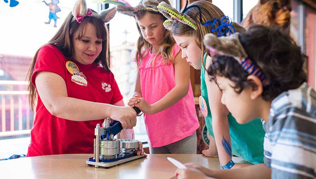 an employee showing kids how to make buttons