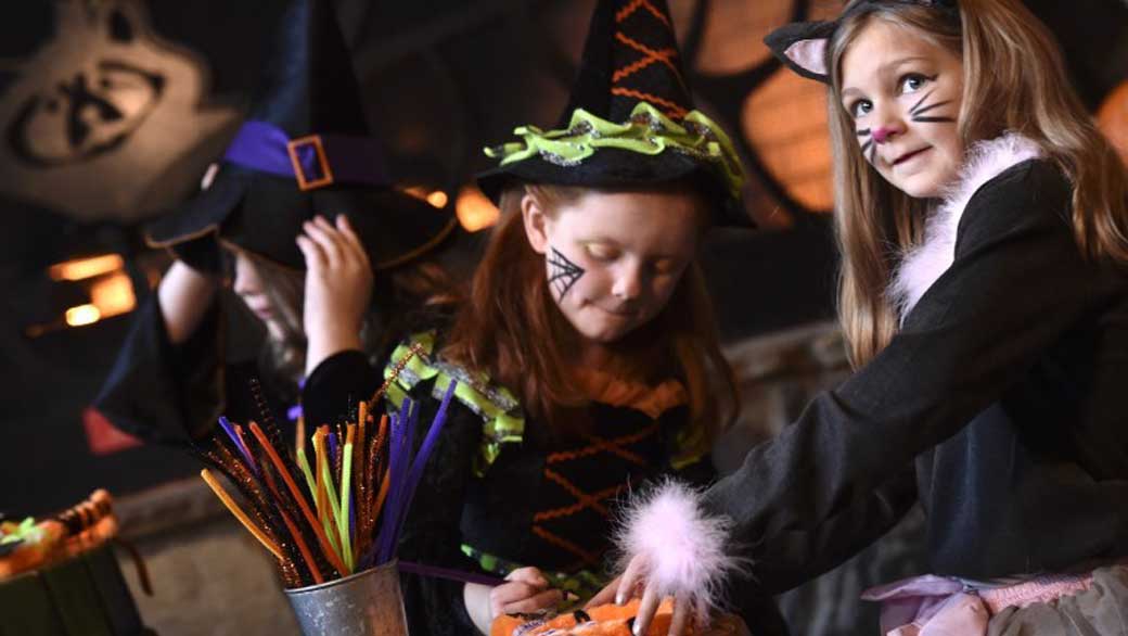 kids dressed in Halloween costumes doing a crafts project