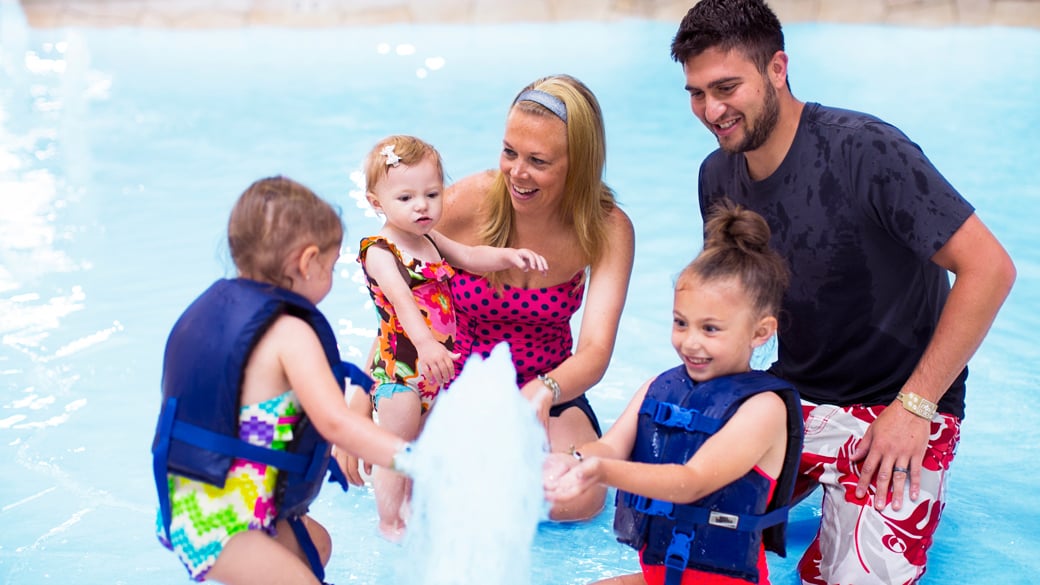 Family having fun at Cub Paw Pool located in a Great Wolf Lodge indoor water park and resort.