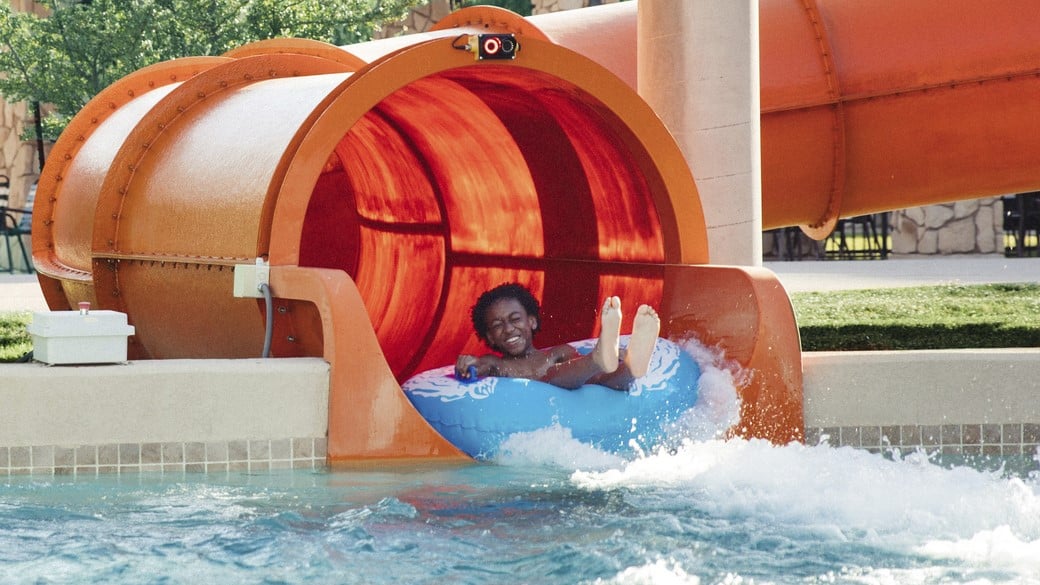 guest riding a tube come out of a water side