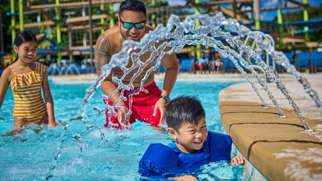 Father is enjoying outdoor pool with his son and daughter