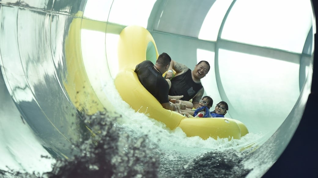 2 fathers enjoying a water slide with kids