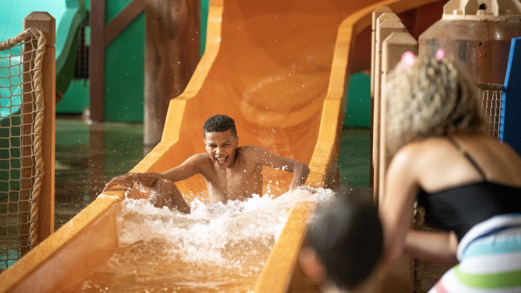 A girl smiles as she rides a water slide