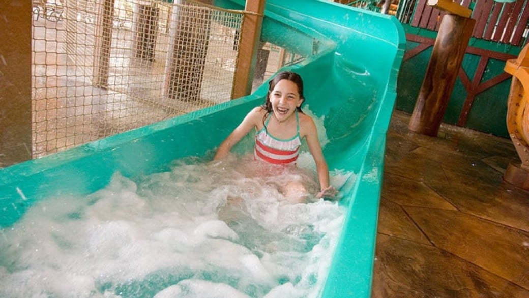 A girl smiles as she rides a water slide