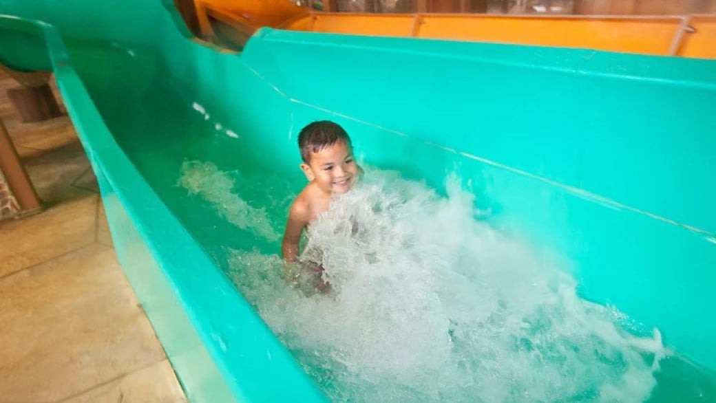 A boy smiles as he slides down the water slide at totem towers