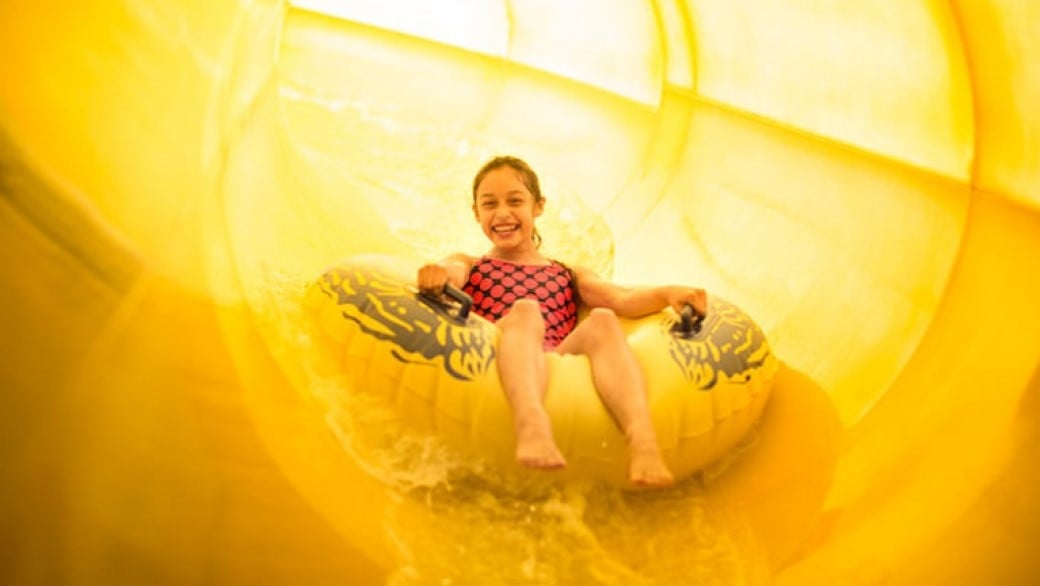 A girls rides a tube down Triple Thunder at Great Wolf Lodge indoor water park and resort.